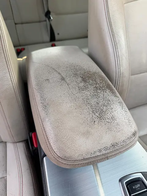 Worn BMW leather center armrest before repair in Denver