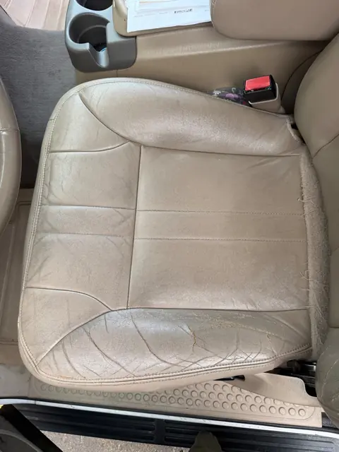 Cracked and worn leather driver seat before restoration in Denver