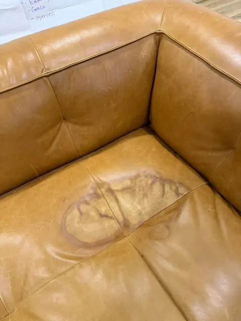 Dark stain on tan leather sofa cushion before removal in Denver
